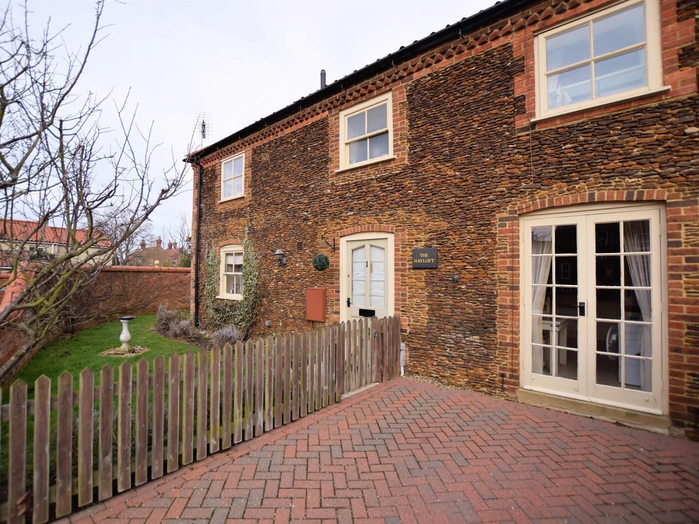 A brick building with a stone facade, a wooden fence, and a paved walkway.