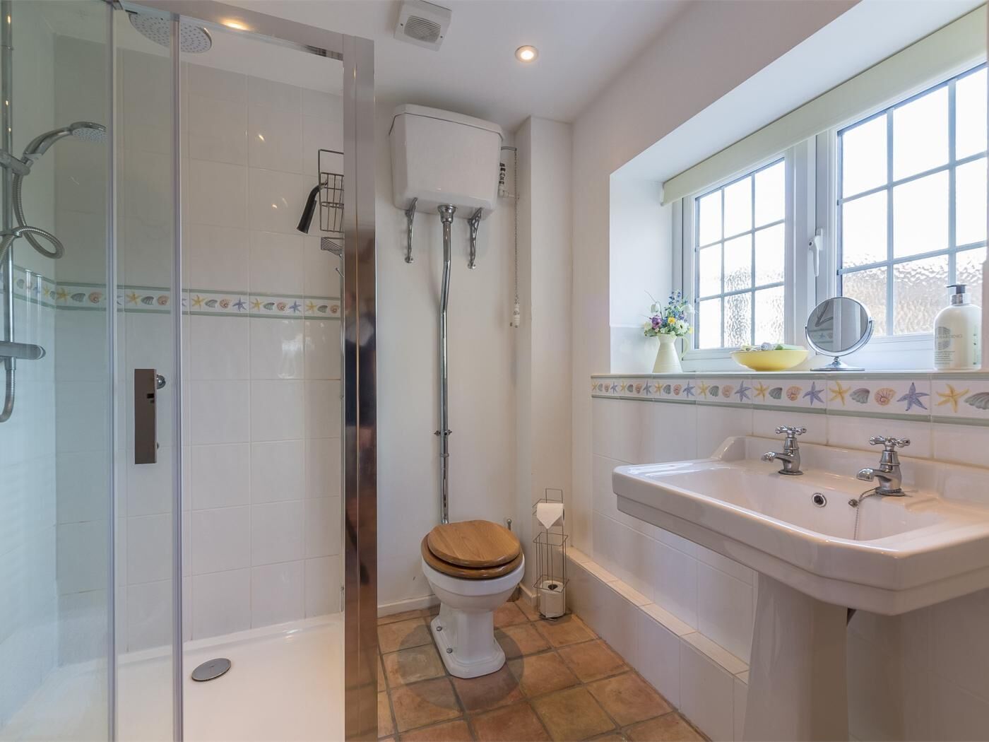 A bathroom with a glass-enclosed shower, a toilet, a bathtub, and a sink with a window above.