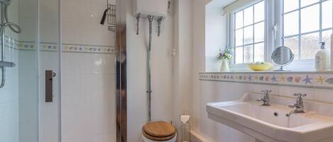 A bathroom with a glass-enclosed shower, a toilet, a bathtub, and a sink with a window above.