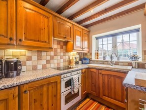 A kitchen with wooden cabinets, a Bosch coffee maker, a bread box, and a window with a view. - 3 Bed in Syderstone (oc-kt083) (Syderstone)