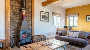 Ein gemütliches Wohnzimmer mit Steinwand, Kamin, einer Couch und einem Couchtisch.