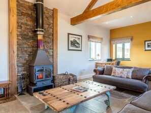 A cozy living room with a stone wall, a fireplace, a sofa, and a coffee table. - 4 Bed in Denbigh (oc-62947) (Llannefydd)