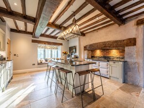 A kitchen with a large island, bar stools, and a hanging light fixture. - 4 Bed in Denbigh (oc-62947) (Llannefydd)