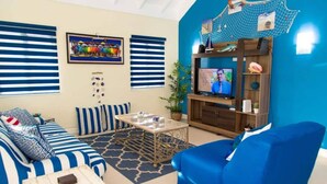A living room with a sofa, a coffee table, a TV, and a bookshelf. - Coolshade - Richmond Estate  (St. Ann Parish)