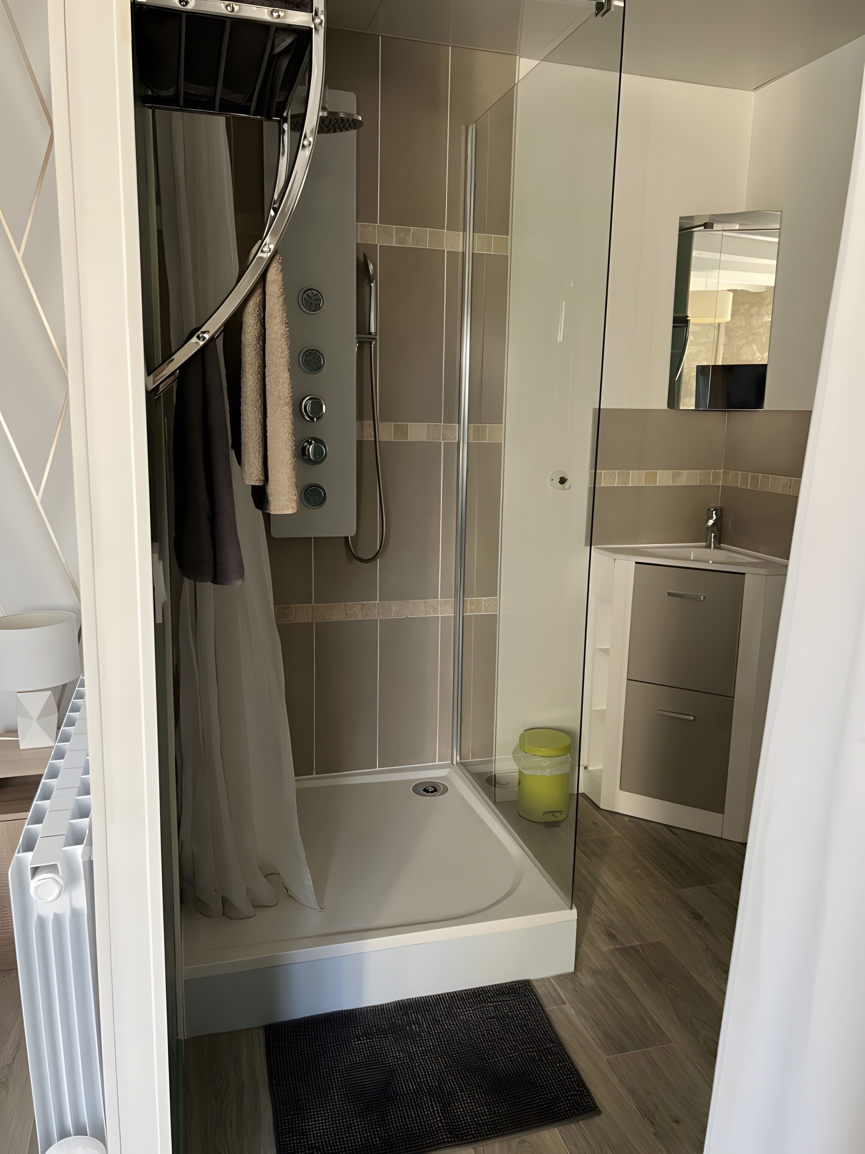 Un baño moderno con ducha de vidrio, lavamanos y espejo.