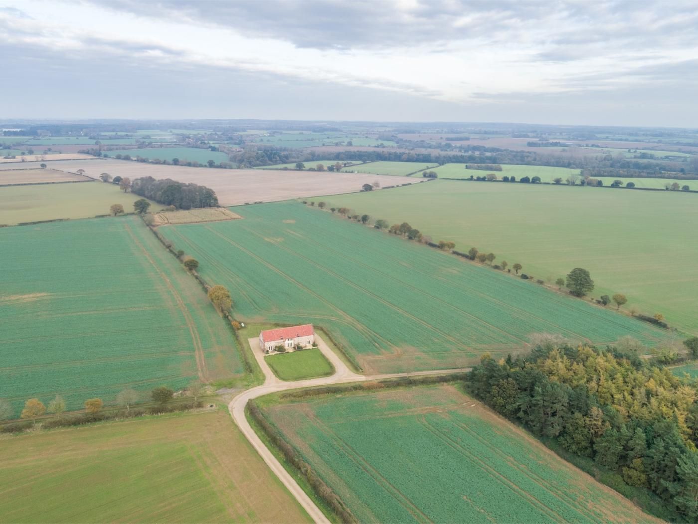 Une vue aérienne d’un paysage rural avec des champs, une ferme et une route.