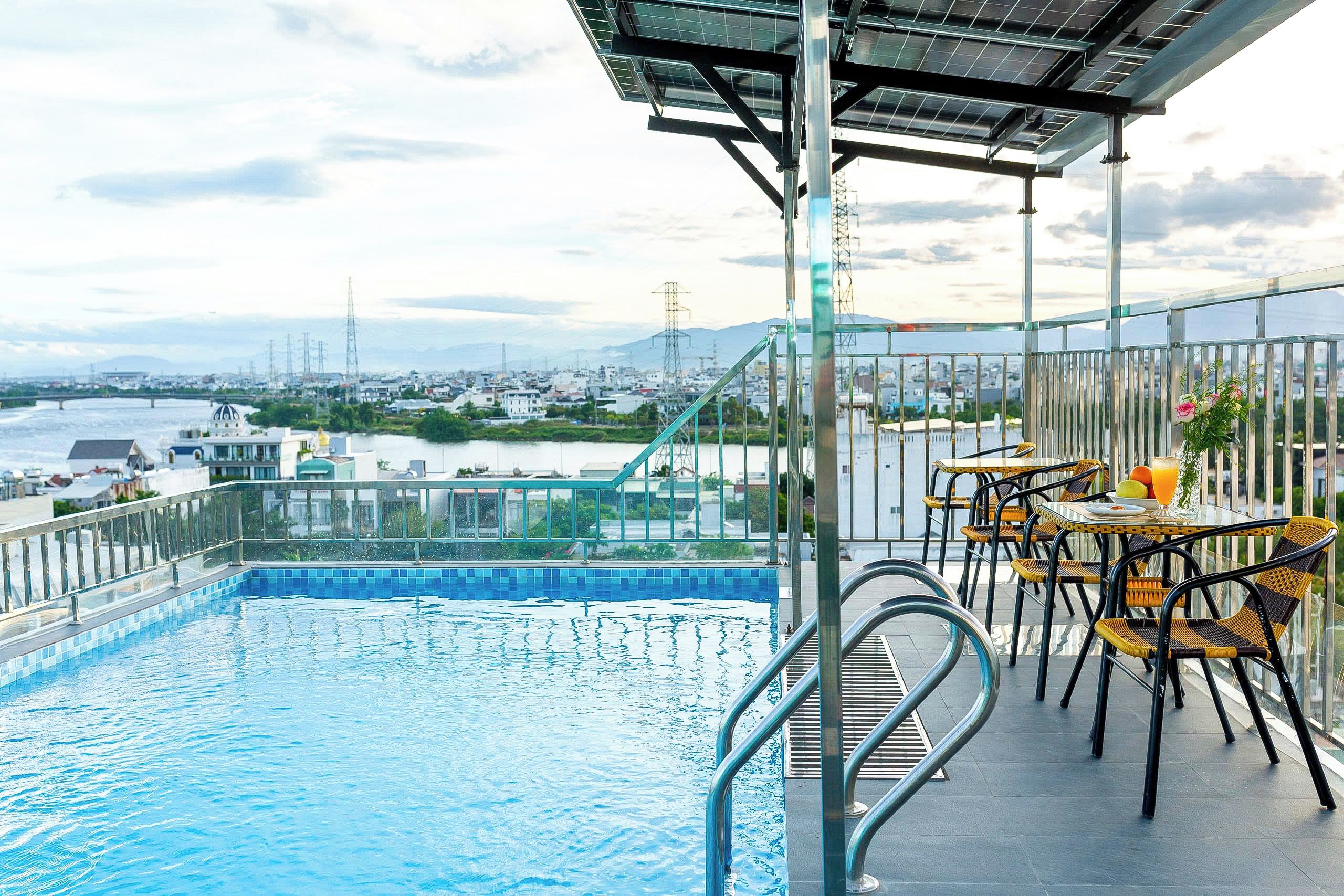 A rooftop pool with a view of a cityscape, including a river and distant mountains.