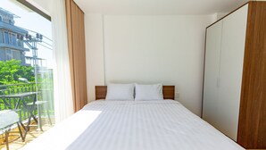 Un dormitorio con cama, armario de madera y balcón con mesa y sillas.