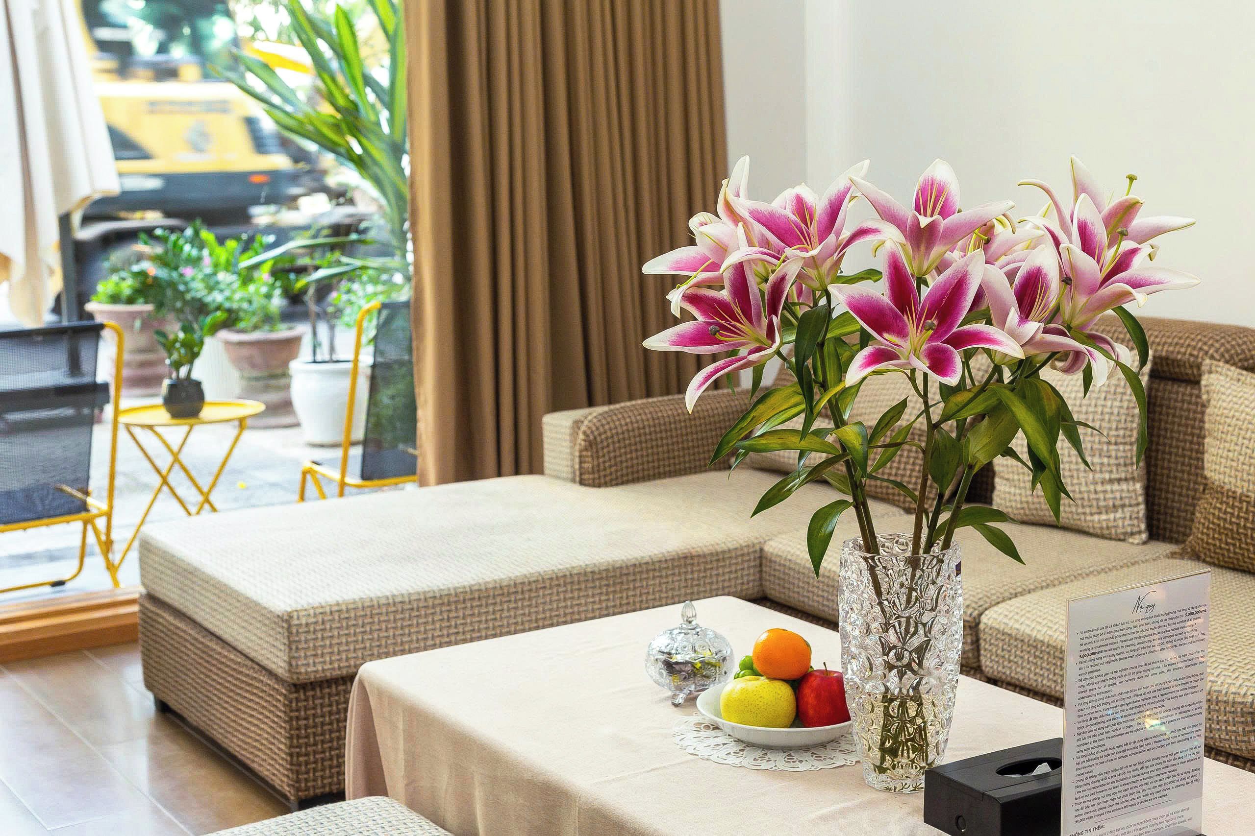 Ein Wohnzimmer mit einer Couch, einem Couchtisch mit Blumen und einer Schale Obst.