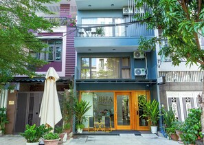 A two-story building with a ground-level entrance, a balcony, and a sign indicating a business establishment. - The BHA Riverside (Da Nang)