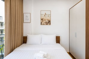 A hotel room with a bed, a headboard, a wardrobe, and two framed pictures on the wall. - The BHA Riverside (Da Nang)