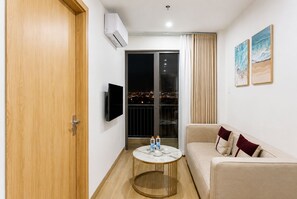 Een moderne woonkamer met een bank, een rond salontafeltje en een tv die aan de muur hangt.