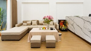 Una sala moderna con un sofá modular, una mesa de comedor con frutas y un altar decorativo.