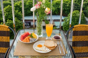A table with breakfast items, a glass of orange juice, and a vase with flowers. - The BHA Riverside (Da Nang)