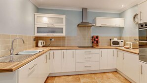 Eine moderne Küche mit weißen Schränken, einer Edelstahl-Spüle, einer Mikrowelle und einem Backofen.