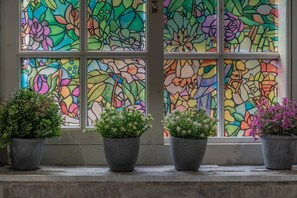 A window with colorful stained glass and four potted plants on a ledge. - 1 Bed in Gainsborough (oc-66230) (Heapham)