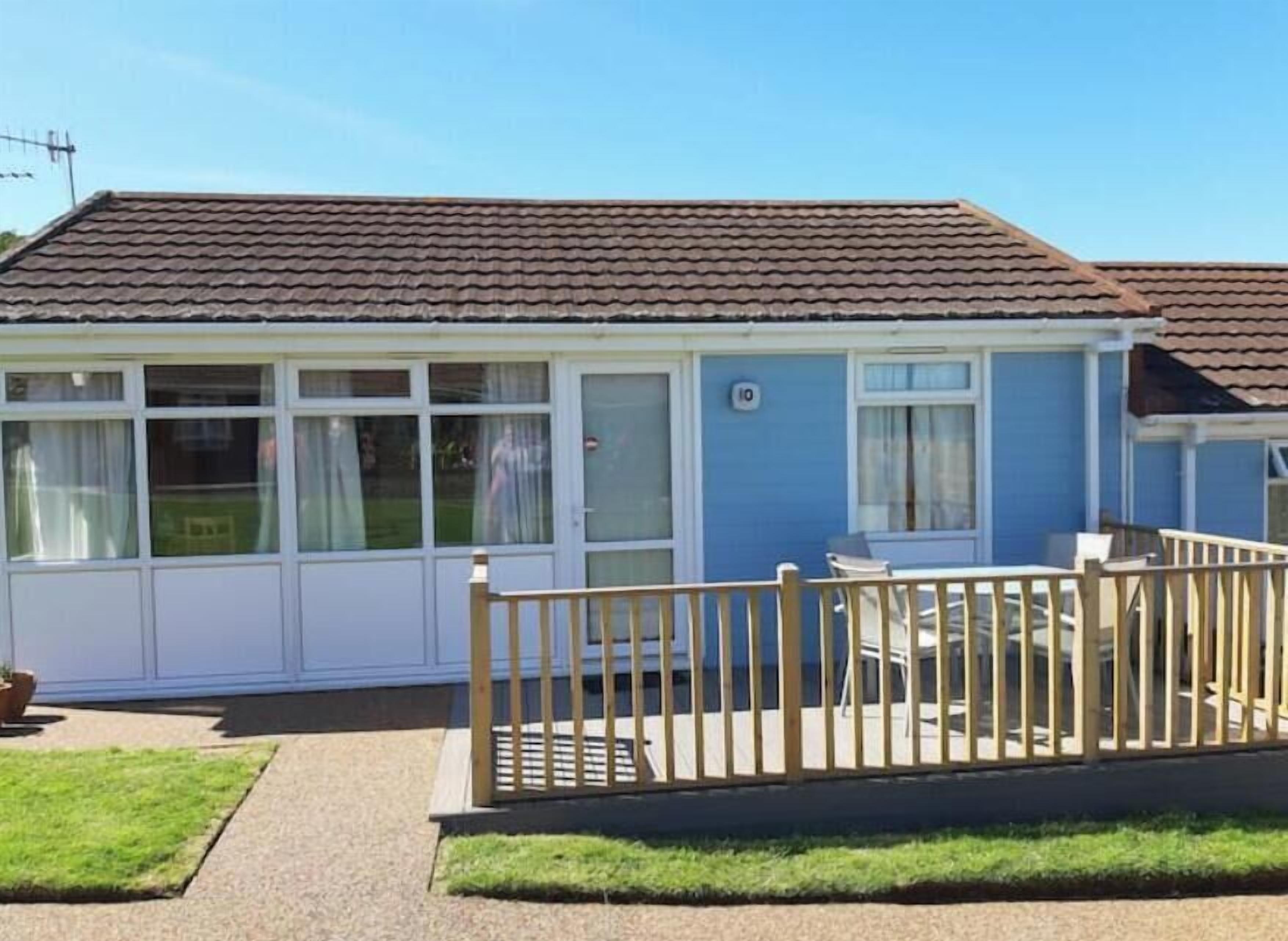Une maison de plain-pied avec une terrasse entourée d’une clôture.