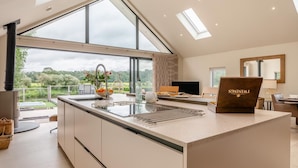 A modern kitchen with a large island, a dining area, and a view of the outdoors. - 3 Bed in Blackburn (oc-64911) (Balderstone)