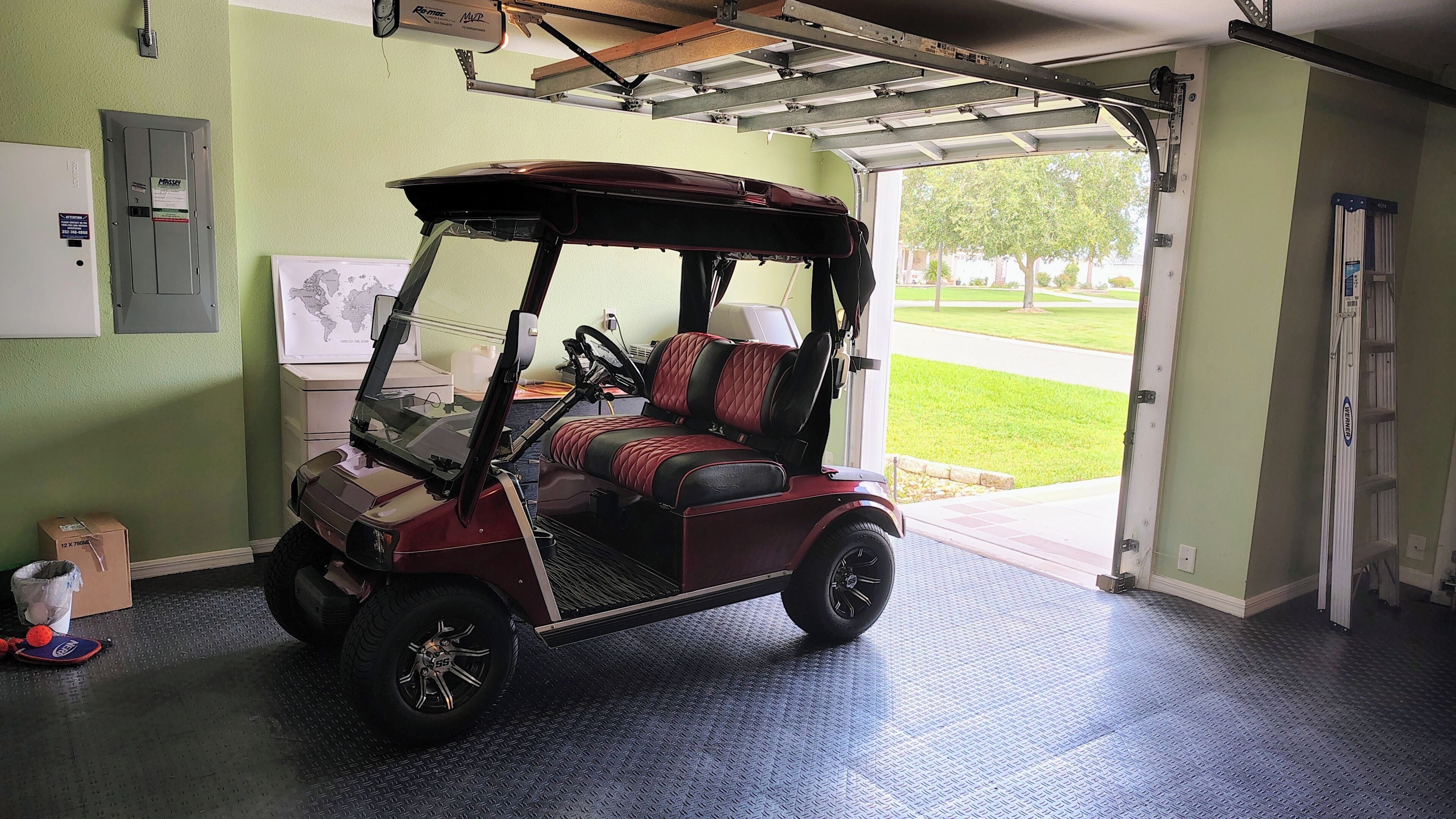 Ein Golfmobil steht in einer Garage mit Metallbedachung und einer Tür zum Freien.