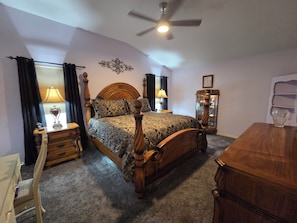 A bedroom with a four-poster bed, a ceiling fan, a nightstand with a lamp, a dresser, and a mirror. - Near Lake Sumter and Brownwood, Gorgeous 3 bedrm/2 bath with Golf Chart and Spa (The Villages)