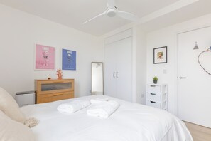 Ein Schlafzimmer mit einem Bett, einer Kommode, einem Spiegel und zwei Bildern an der Wand.