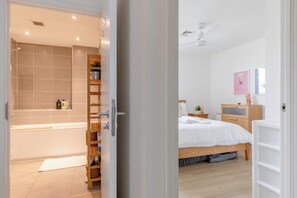 A modern bathroom with a bathtub, shower, and a shelf with toiletries. - Funky 1 BDR High Rise Flat City Views Angel (London)