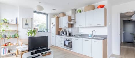 A modern kitchen with white cabinets, a built-in oven, and a microwave.