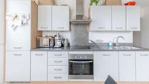 Ett modernt kök med vita skåp, en inbyggd ugn, en kaffemaskin och en diskho i rostfritt stål.