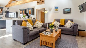 Ein modernes Wohnzimmer mit zwei Sofas, einem Couchtisch und einer Küche im Hintergrund.