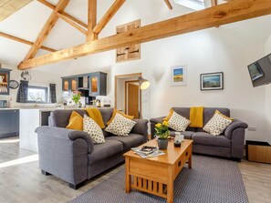 Ein modernes Wohnzimmer mit zwei Sofas, einem Couchtisch und einer Küche im Hintergrund.