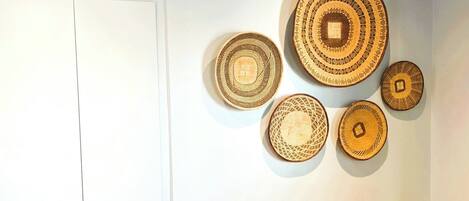 A room with a bed, a wall with circular woven art pieces, and a door.