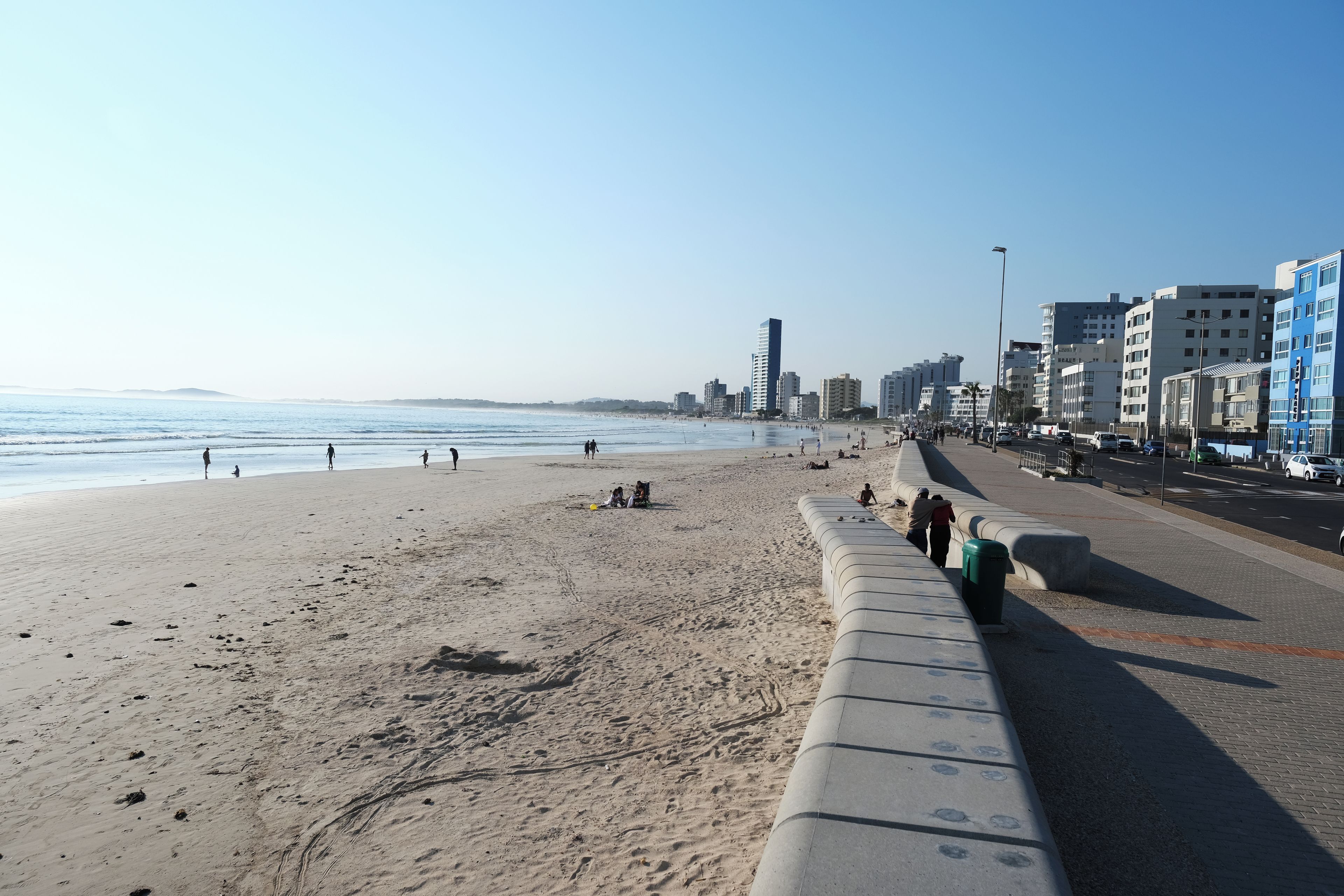 Une plage où une barrière en béton sépare le sable de la route.