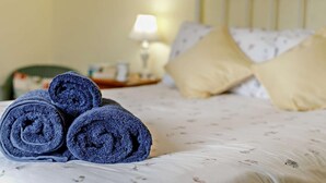 A bed with rolled towels, a lamp, and a nightstand in a hotel room. - 3 Bed in Fowey (oc-66074) (Polruan)