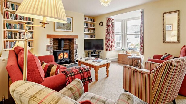 A cozy living room with a fireplace, bookshelves, a television, and comfortable seating. - 3 Bed in Fowey (oc-66074) (Polruan)
