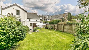A residential property with a well-maintained lawn, a wooden fence, and a white house with a visible garage. - 3 Bed in Fowey (oc-66074) (Polruan)