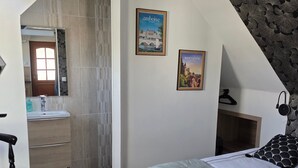 Un dormitorio con cama, cómoda, espejo y baño con lavamanos y espejo.