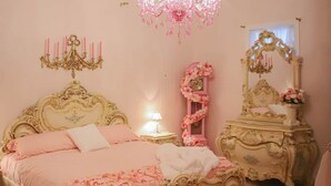Ein Schlafzimmer mit einem großen Bett, einer Kandelaber, einem Schminktisch und einem Spiegel.