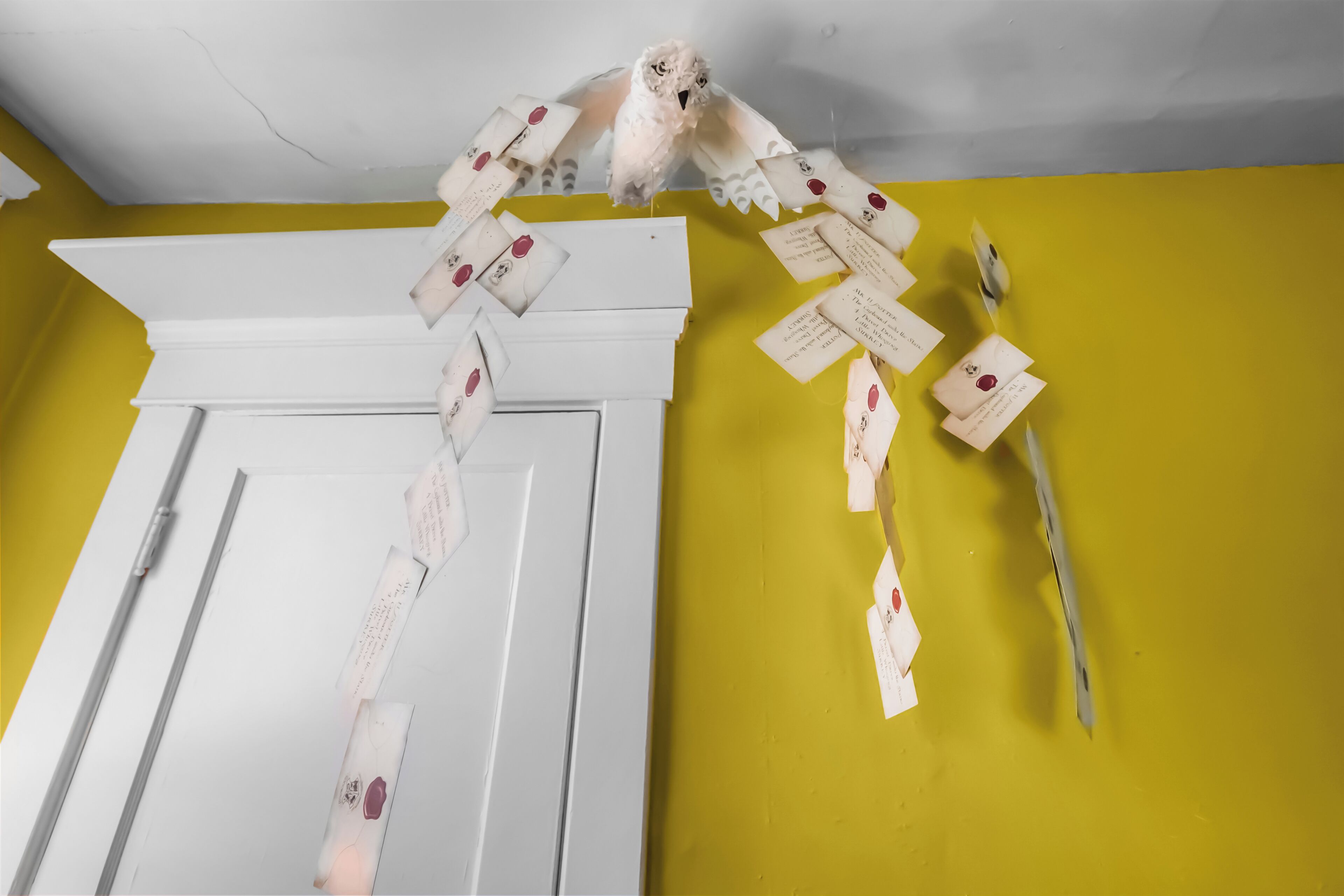 A room with a yellow wall, a white door, and a ceiling with visible cracks.