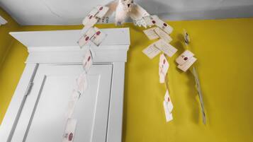 A room with a yellow wall, a white door, and a ceiling with visible cracks.