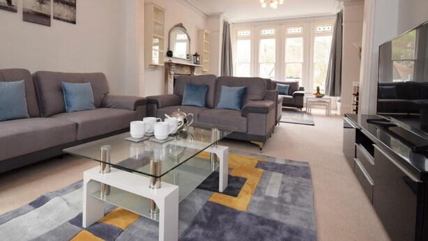 A modern living room with a sofa set, a glass coffee table, and a flat-screen TV. - 4 Bed in Ilfracombe (oc-66202) (Ilfracombe)