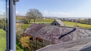 Een landelijk landschap met een stenen gebouw, een houten hek en een heldere lucht.