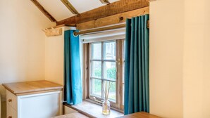 A corner room with a window, wooden beams, a small table, and a cabinet. - 2 Bed in South Creake (oc-kt117) (South Creake)