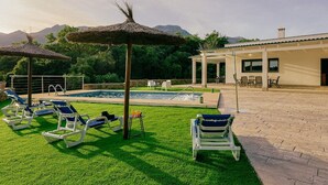 A pool area with lounge chairs, a table with drinks, and a building with a patio. - Villa La Huerta by Hacienda Alfacara (Benadalid)