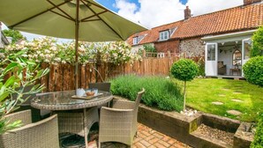 A patio with wicker furniture, a table, and a large umbrella. - 2 Bed in Syderstone (oc-kt197) (Syderstone)