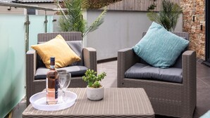 A wicker outdoor seating area with cushions, a bottle, and a glass on a tray. - 2 Bed in Bideford (oc-65074) (Northam)