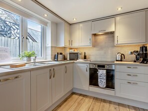 Eine moderne Küche mit weißen Schränken, einem eingebauten Ofen und einem Fenster mit Blick auf einen Holenzaun.