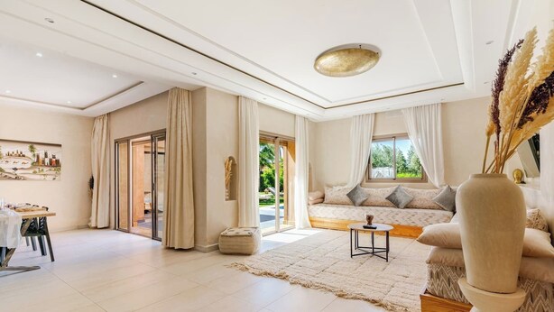 En rummelig opholdsstue med sofa, spisebord og stort vindue.