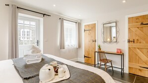 Ein Hotelzimmer mit einem Bett, einem Schreibtisch, einem Stuhl, einem Spiegel und Blick ins Freie.