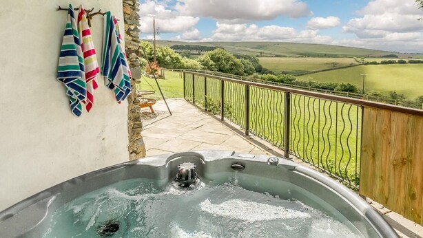 Ein Whirlpool auf einem Balkon mit Blick auf eine grüne Landschaft.