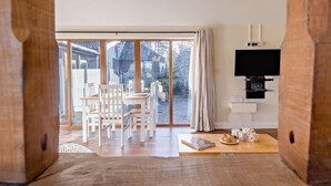 Una habitación moderna con comedor, televisión y vistas a través de amplios ventanales.